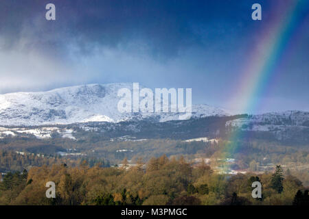 Windermere, Cumbria, UK Weather : Après de nouvelles du jour au lendemain la neige et plus dans la prévision d'un arc-en-ciel apparaît sur le lac Windermere avec les montagnes couvertes de neige dans la distance, Cumbria, Royaume-Uni Banque D'Images