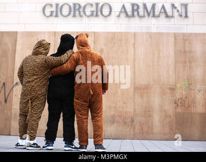 Trois carnival festivaliers habillés comme des prédateurs, se tenir en face du logo de 'Giorgo Armani' pendant la Rosenmontag (Lundi Gras) carnival procession à Duesseldorf, Allemagne, 12 février 2018. Photo : Ina Fassbender/dpa Banque D'Images