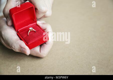 Boîte cadeau rouge ouvert avec anneau de diamant dans mans mains. Concept de l'anneau d'enclenchement, Saint Valentin cadeau surprise, symbole de vie. Banque D'Images