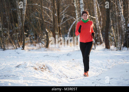 Photo de jeune fille sur sports courir à travers la forêt d'hiver Banque D'Images