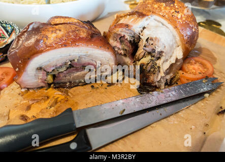 Joints de rôti de porc sur une planche avec deux couteaux à découper. Banque D'Images