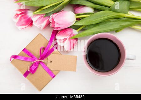 Journée des femmes. Bouquet de tulipes roses et un cadeau sur fond de bois blanc, vue du dessus Banque D'Images