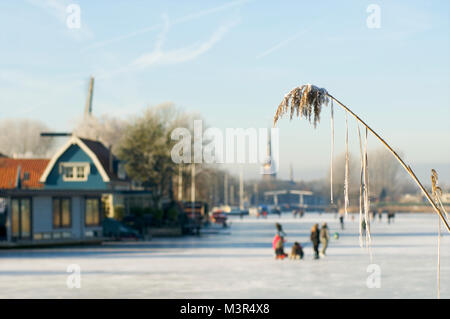 Les gens le patinage et les randonnées sur la rivière gelée de Vecht avec moulins à vent et la ville de Montluçon en arrière-plan, les Pays-Bas Banque D'Images