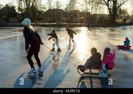 Jeune mère avec des enfants tirant un traîneau et le patinage sur glace ensemble dans les Pays-Bas Banque D'Images