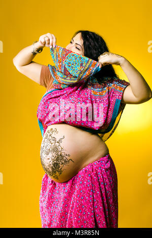 Happy pregnant woman in Indian sari, le ventre et les mains au henné peints Banque D'Images