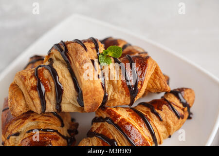 Des croissants frais avec du sirop de chocolat sur un fond gris clair, copiez l'espace. La cuisine française dessert concept. Banque D'Images