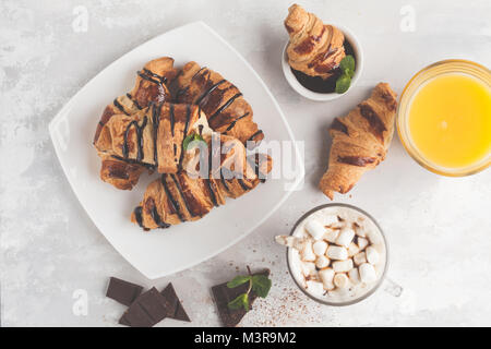 Petit-déjeuner frais composé de croissants avec du sirop de chocolat, jus d'orange et de cacao avec marshmelow. Banque D'Images