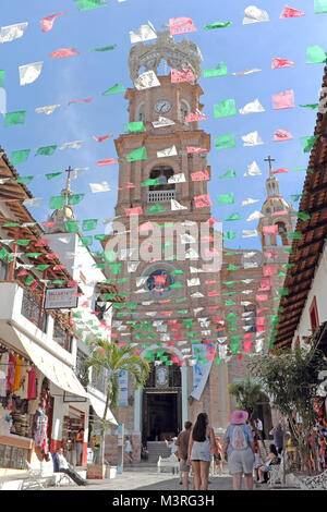 Papel picado drapeaux volent au-dessus de la rue piétonne menant à l'emblématique Église de Notre Dame de Guadalupe à Puerto Vallarta, au Mexique. Banque D'Images