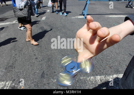 Un enfant tourne une fidget spinner sur son pouce dans une rue de Brooklyn new york USA Banque D'Images