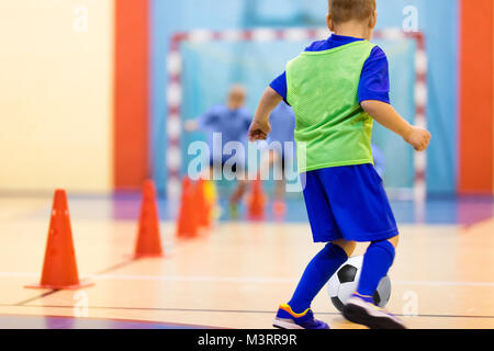 La formation du football dribbles. forage conique Futsal Football formation pour les enfants. Jeune joueur de soccer intérieur avec un ballon de soccer dans une salle de sport. Dvd dans Banque D'Images