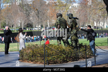 Tourisme et les visiteurs affluent au National Mall à visiter les trois militaires (parfois appelés les trois soldats) statue sur la Journée des anciens combattants du Vietnam. La statue située sur le National Mall à Washington D.C. Près de la Vietnam Veteran's Memorial Wall. La statue représente trois soldats, volontairement identifiables comme European American, Afro-américaines et hispano-américaine. Dans leur arrangement final, la statue et le mur semblent interagir entre eux, avec les soldats au spectacle en hommage solennel au nom de leurs camarades tombés au combat. La distance entre les deux leur permet de Banque D'Images