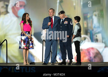 Le Président George Bush se tient sur scène avec Air Force Master Sgt. Israël Del Toro et sa famille s'exprime lors de la cérémonie d'à elles 2016 Invictus de 2010 à Orlando, en Floride, le 8 mai 2016. Dans l'arrière-plan, une photo de la visite de Bush Del Toro à l'hôpital. (DoD News photo par EJ Hersom) 160508-D-DB155-014 par DoD Nouvelles Photos Banque D'Images