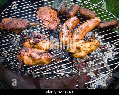 Vue de dessus sur une variété de viande et des saucisses sur un barbecue au charbon de rack la braise. Banque D'Images