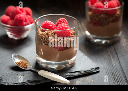 Dessert au chocolat dans les verres avec les framboises. Mousse au chocolat ou au lait en partie lunettes avec les baies fraîches, Close up. Banque D'Images