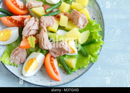 Salade niçoise au thon, oeufs, pommes de terre, haricots verts et tomates. Salade niçoise traditionnelle bleu sur fond de bois, Close up. Banque D'Images