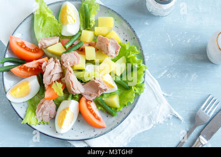 Salade niçoise au thon, oeufs, pommes de terre, haricots verts et tomates. Salade niçoise traditionnelle bleu sur fond de bois, vue du dessus, copiez l'espace. Banque D'Images