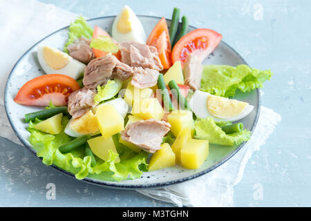 Salade niçoise au thon, oeufs, pommes de terre, haricots verts et tomates. Salade niçoise traditionnelle bleu sur fond de bois, Close up. Banque D'Images