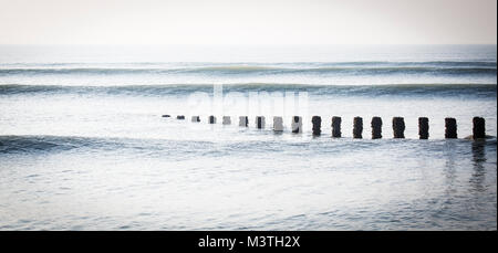 Une série de vagues se brisant sur un brise-lames en bois sur la plage de Littlehampton, West Sussex Banque D'Images