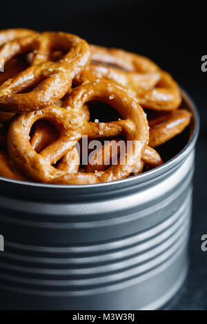 Bretzels croustillants apéritif dans un pot en métal sur un tableau noir. Lumière mystique style. Banque D'Images