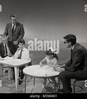 Années 1960, historique, l'image montre une jeune fille et un garçon assis à de petites tables dans un studio de télévision participant à la télévision sur les enfants américains les plus brillants de la concurrence, USA. Banque D'Images