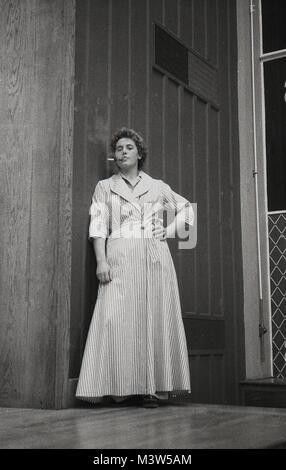 1940, historiques, une actrice Dame vêtue d'un peignoir ou robe de chambre essayant de paraître sophiscated byt fumer une cigarette à travers un porte-cigarette, sur une scène dans une pièce de théâtre, England, UK. Théâtre amateur était une activité de loisirs populaire en Grande-Bretagne d'après-guerre en ce moment. Banque D'Images