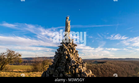 Prise de vue au grand angle de low angle de vue d'une statue de la Vierge Marie avec la lune et les nuages sur l'arrière-plan. Banque D'Images