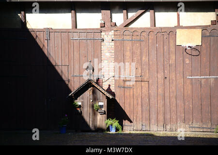 Une grange avec deux grandes portes en bois et une petite maison de décoration. Banque D'Images