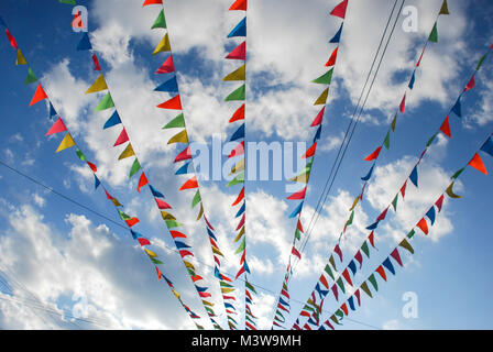 Drapeaux triangulaires multicolores et suspendus au vent sous un ciel bleu, un jour ensoleillé Banque D'Images