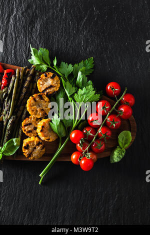 Légumes grillés sur un plateau en bois sur une ardoise noire. copie espace, frais généraux shot Banque D'Images