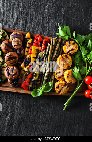 Un grand plateau en bois avec un snack d'été, barbecue coloré de légumes, tomates cerises et verts. été délicieux aliments sains pour une grande entreprise de Banque D'Images