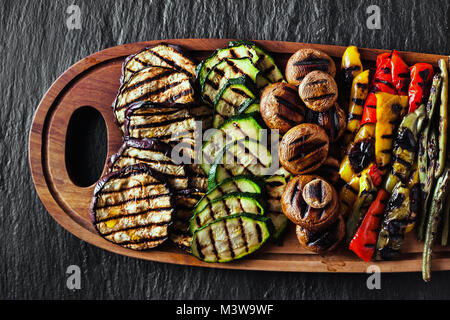 Un grand plateau en bois avec un snack d'été, barbecue coloré de légumes, tomates cerises et verts. été délicieux aliments sains pour une grande entreprise de Banque D'Images