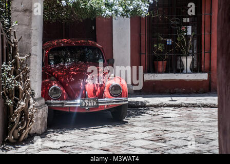 Une Volkswagen Coccinelle rouge garée dans la cour d'une maison coloniale traditionnelle au Pérou Banque D'Images