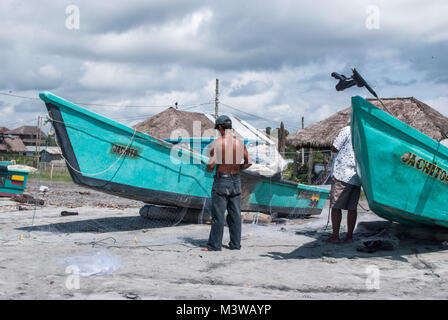 Deux pêcheurs préparent à lancer leurs bateaux sur une plage en Equateur Banque D'Images