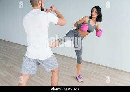 Boxer femme MMA Fighter pratique ses compétences avec un entraîneur personnel dans la salle de sport Banque D'Images