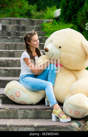 Belle jeune fille dans l'escalier dans le parc en admirant ses énormes ours Banque D'Images