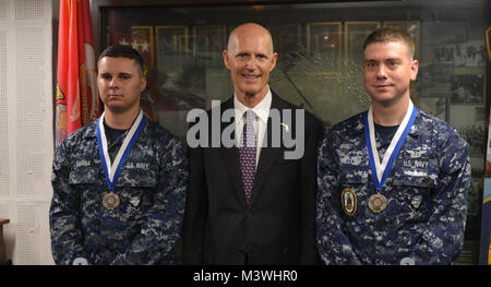 170607-N-RL456-0152 MAYPORT, Floride (7 juin 2017) Florida Gov. Rick Scott, centre, pose pour une photo avec un membre de la David Barba, à gauche, et l'Aviation maître de Manœuvre (fossiles) 3e classe Andrew Miller dans le Suribachi Prix à bord du navire d'assaut amphibie USS Iwo Jima (DG 7) après un appel mains libres. Au cours de l'ensemble du personnel appel, Scott a remis la Médaille du Mérite de la Floride à Miller et Barba, qui ont fourni de l'aide aux victimes de l'attentat de Times Square le 18 mai. (U.S. Photo par marine Spécialiste de la communication de masse 2e classe Hunter S. Harwell/libérés) 170607-N-RL456-0152 Conservateur Photographie par Banque D'Images