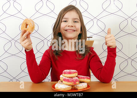 Happy little girl avec des beignets sucrés et thumb up Banque D'Images