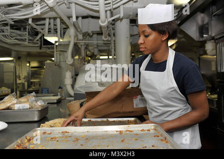 Golfe d'Oman (15 juillet 2013)--spécialiste culinaire Seaman Sydney Jordan de Los Angeles, prépare du poulet pané à bord du porte-avions USS Nimitz (CVN 68). Un groupe d'intervention de Nimitz est déployé sur le 5e Flotte des États-Unis zone de responsabilité des opérations de sécurité maritime, les efforts de coopération en matière de sécurité dans le théâtre et missions d'appui pour l'opération Enduring Freedom. (U.S. Photo par marine Spécialiste de la communication de masse Seaman Apprentice Aiyana/Pascal) Parution Juillet 15 30 Lot de 31 par l'USS NIMITZ (CVN 68) Banque D'Images