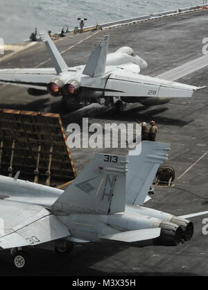 La mer d'Oman (16 août 2000 30, 2013) Un F/A-18E Super Hornet, haut, affecté à la "Argonautes" de Strike Fighter Squadron (VFA) 147 se prépare à lancer sur le pont d'envol du porte-avions USS Nimitz (CVN 68) qu'un F/A-18C Hornet affectés à la "Blue" de Strike Fighter Squadron (VFA) 146 d'attente. Un groupe d'intervention de Nimitz est déployé sur le 5e Flotte des États-Unis zone de responsabilité des opérations de sécurité maritime et les efforts de coopération en matière de sécurité dans le théâtre. (U.S. Photo par marine Spécialiste de la communication de masse Seaman Apprentice Kelly M. Agee/) Parution août 30 6 Lot de 9 à l'USS NIMITZ (CVN 68) Banque D'Images