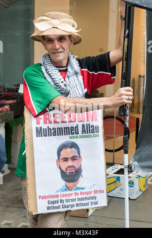 Un homme porte le chapeau elle est tenue pour une femme qui est mise sur un keffieh à la manifestation appelant à la libération de gréviste de la faim palestiniens mourir Muhammed Allan. Banque D'Images