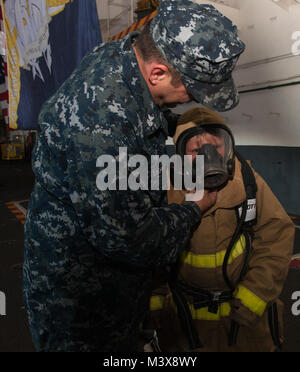 PUGET SOUND, dans l'État (31 juillet 2014) 1ère classe Ordnanceman Aviation Charles Rhodes aide son fils à la fois de Marysville, Washington, mis sur l'équipement de lutte contre les incendies dans la zone du porte-avions USS Nimitz (CVN 68) au cours d'une croisière d'une journée de la famille et amis. Nimitz est retourné à la Station Navale Everett après avoir accueilli plus de 400 amis et membres de la famille au cours d'une croisière d'une journée. (U.S. Photo par marine Spécialiste de la communication de masse de la classe 3ème Kelly M. Agee/libérés) 140731-N-AZ866-057.jpg Banque D'Images