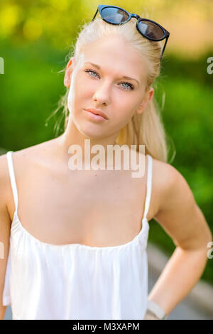 Natural teen blonde girl debout dans la rue, au soleil Banque D'Images