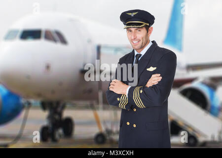 Portrait Of A Smiling Male Pilot avec les mains pliées à l'avant de l'avion Banque D'Images