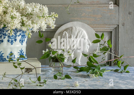 La vie encore français avec des lilas, bleu et blanc fleur antique titulaire et un médaillon en plâtre portrait Banque D'Images