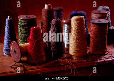 Plusieurs bobines de tissage du coton ou de la laine avec filetage sur eux. Photographie couleur vertical tourné dans un studio avec un éclairage spectaculaire. Ocre foncé Banque D'Images