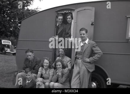 Années 1950, photo historique montrant un grand groupe de la famille, hommes, femmes et enfants et chien de compagnie, assis à l'extérieur et debout à l'entrée de leur maison de vacances Caravane garé dans un champ, England, UK. Banque D'Images