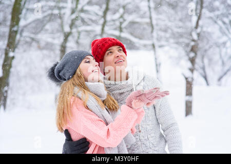 Les adolescents filles et garçons dans les chapeaux et les chandails tricotés pendant les chutes de neige Banque D'Images