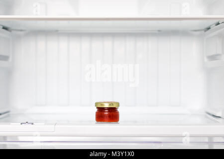 Les vêtements délicats dans un petit verre dans un refrgerator vide. Une petite bouteille de bourrage dans une étagère dans le réfrigérateur. Banque D'Images