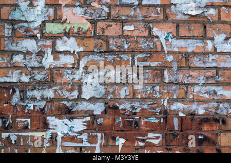 Texture mur de briques rouge foncé avec des annonces. Brickwall brun au hasard ou collés et grattées autocollants. Vieux papiers déchirés, modèle Surface. Banque D'Images