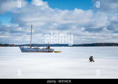 Porvoo, Finlande - le 24 février 2017 : séance de pêcheurs et la pêche sur glace à bright journée d'hiver de Finlande Banque D'Images